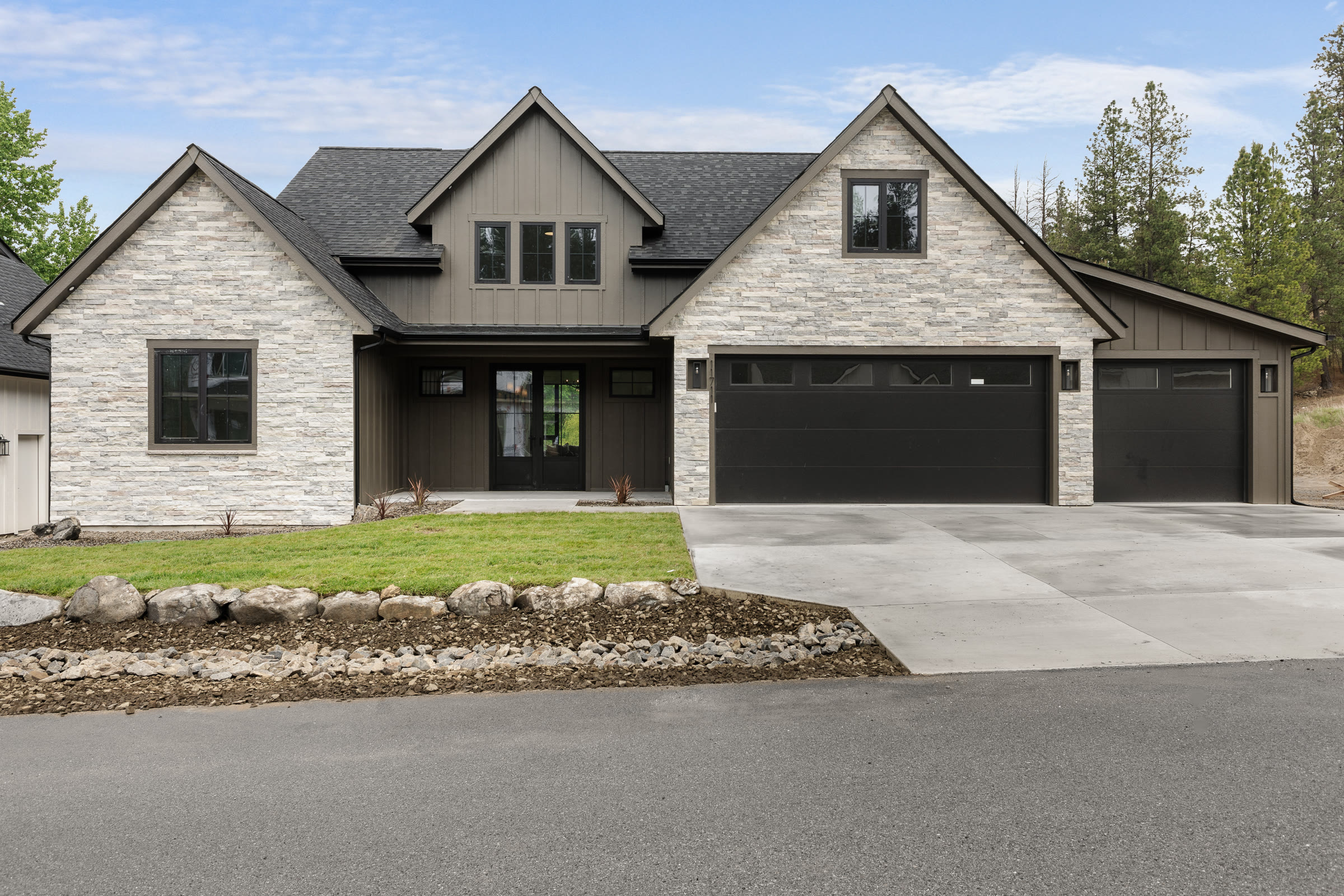 Custom home with stone and board-and-batten siding on a pine-lined property in Eastern Washington