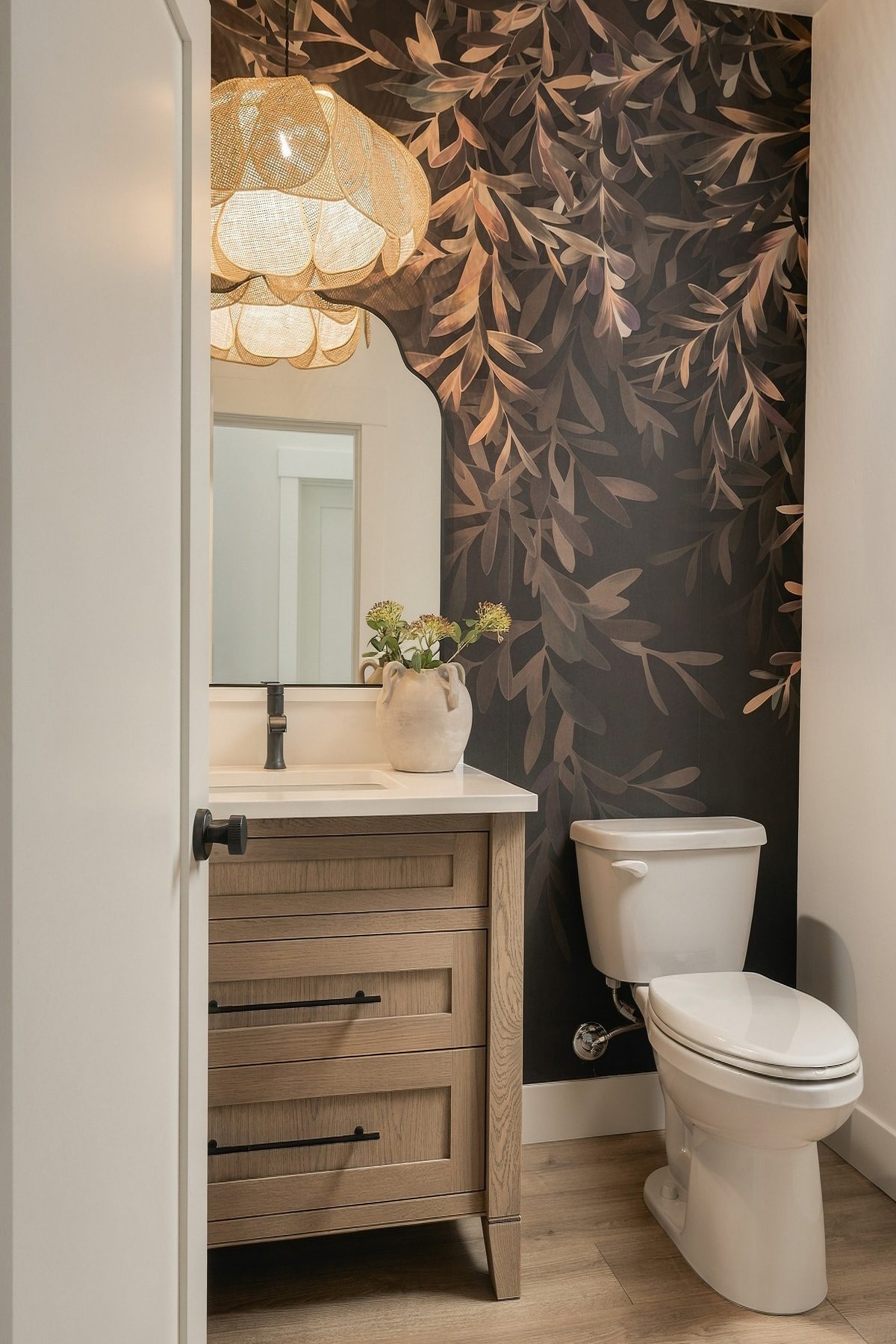 Powder room with botanical wallpaper and a woven pendant