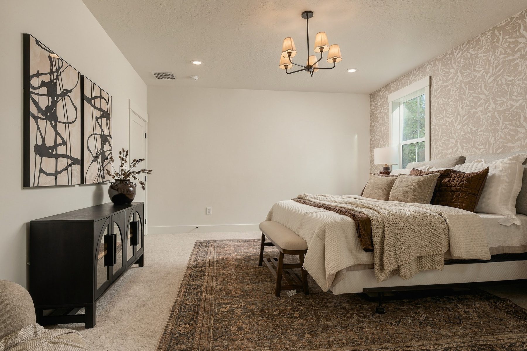 Primary bedroom with a patterned feature wall and chandelier