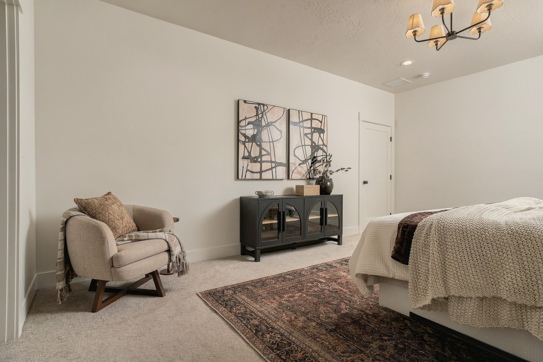 Primary bedroom sitting area with armchair and layered rug