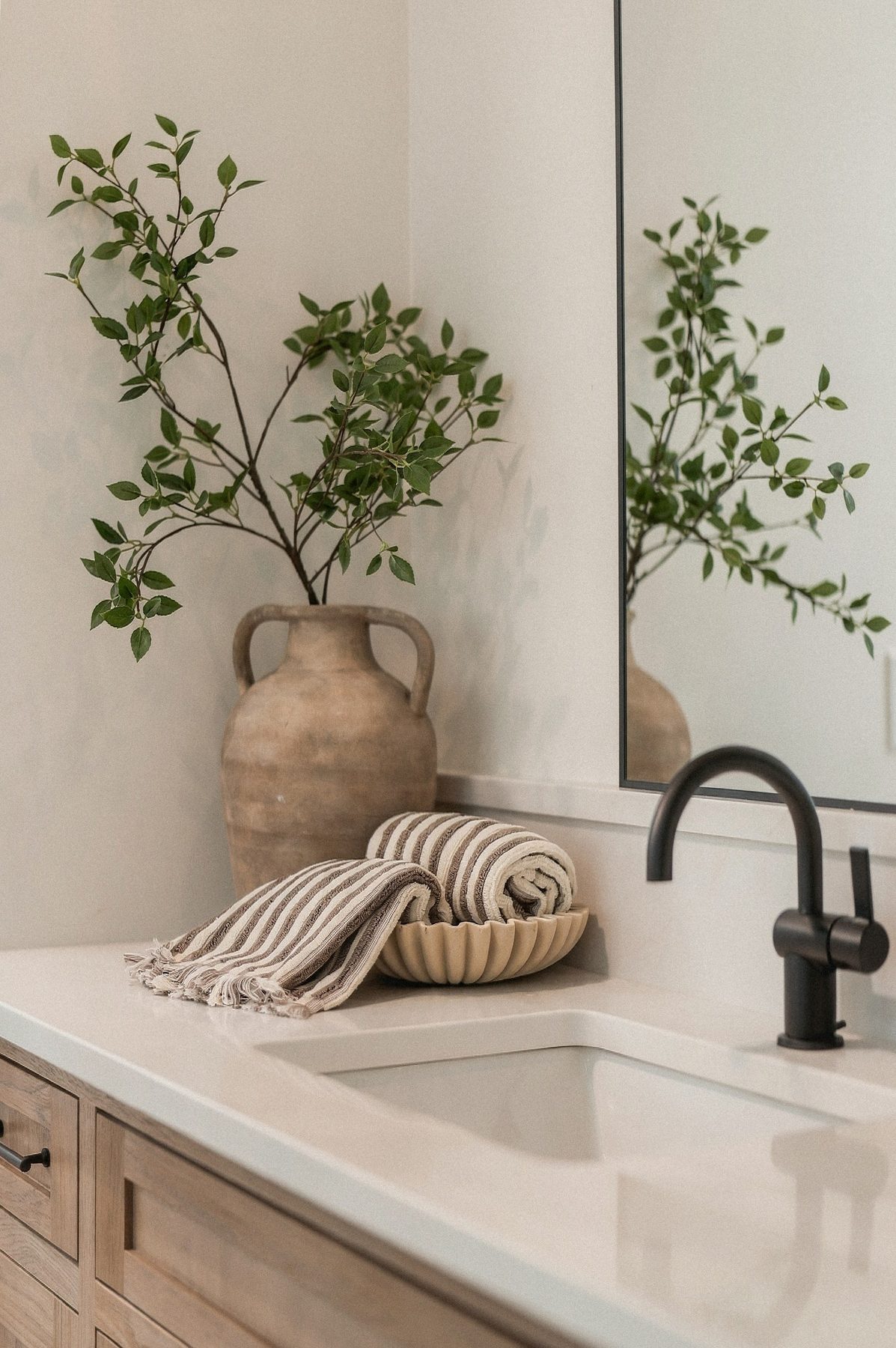 Vanity detail with matte black tapware and olive branches