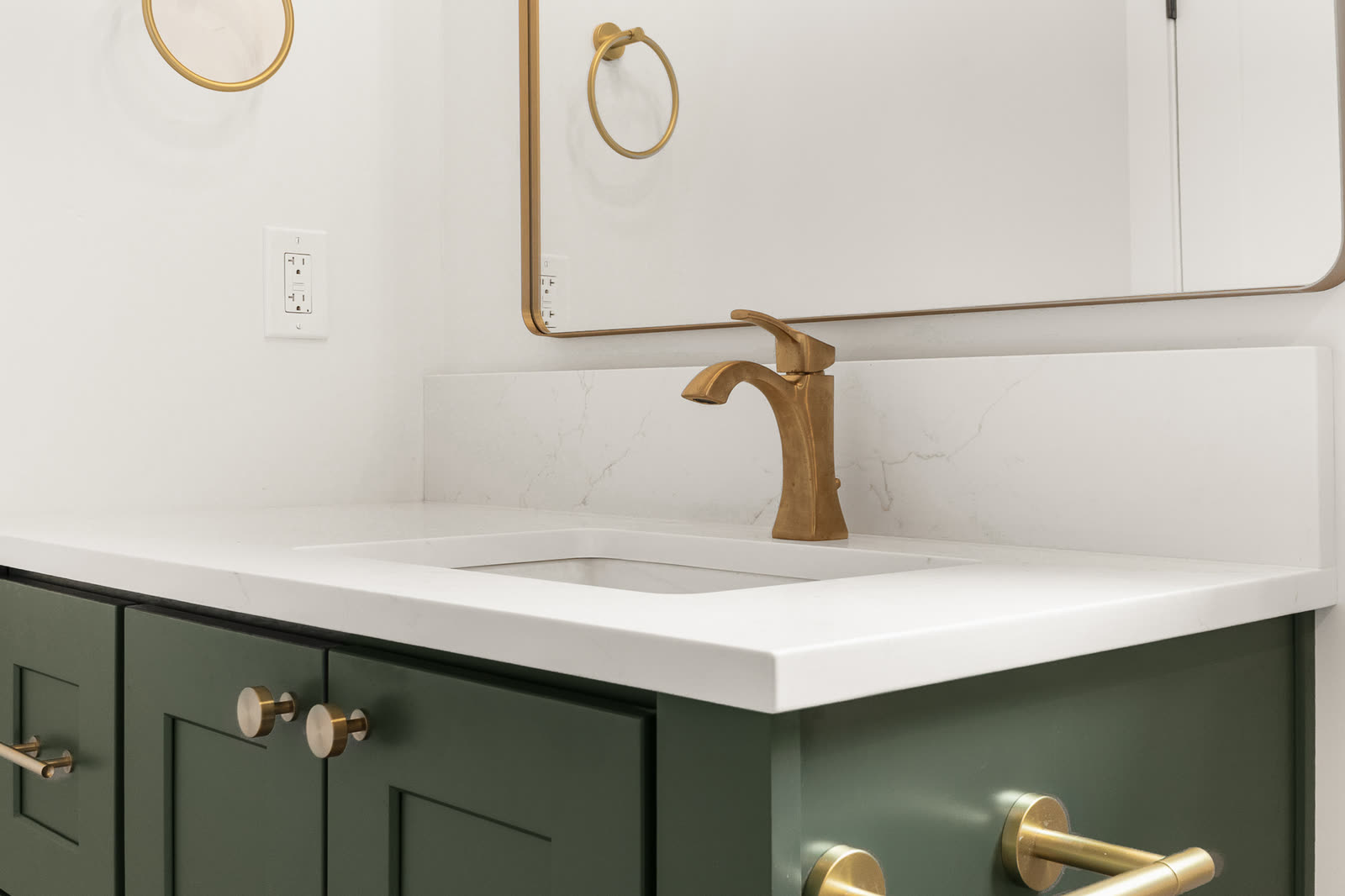 Green vanity cabinetry with brass fixtures